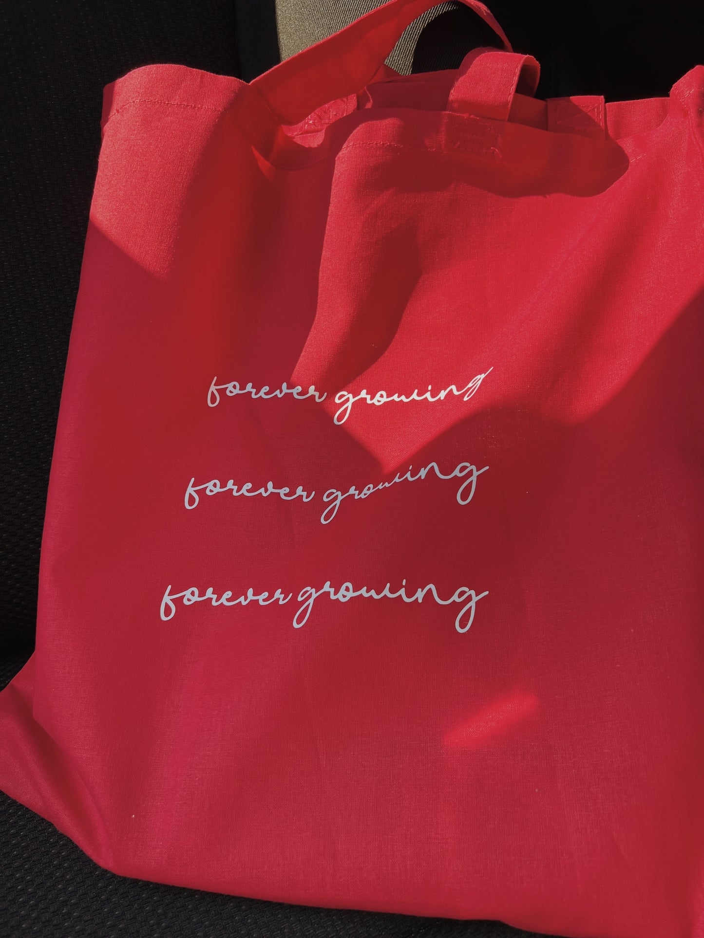 red tote bag with white text on car chair