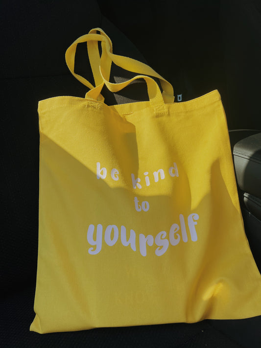 yellow tote bag with white text laying on car chair